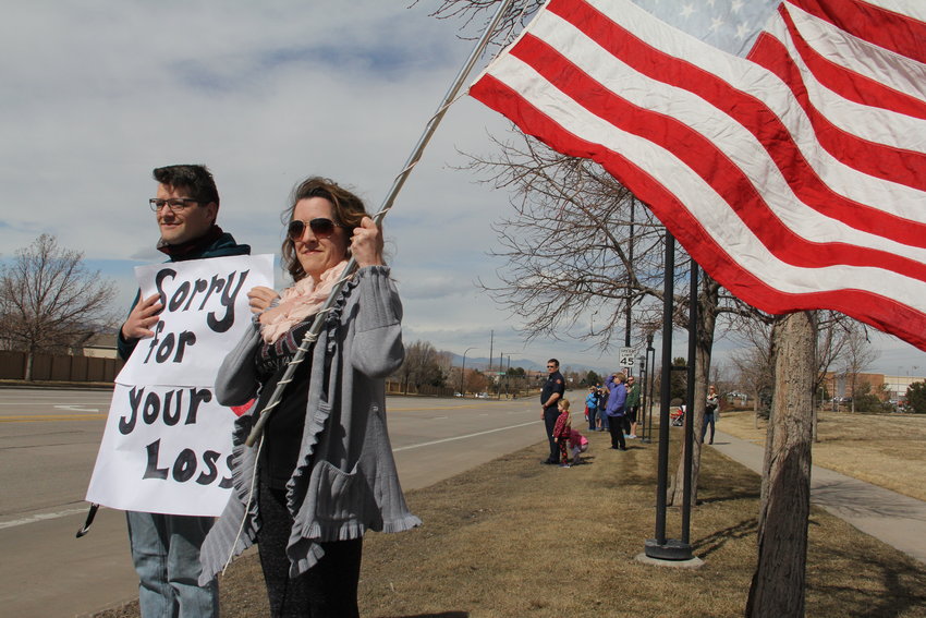 Stacia Martin, 46, and her son, Shaun Martin, 26, hold an American flag and a sign that reads, “Sorry for your loss,” on Lucent Boulevard in Highlands Ranch March 8 as a procession of fire response and police vehicles drives to Mission Hills Church in Littleton, bringing with it Cody Mooney, 31, who died after complications related to a tumor. About a dozen lined up along Lucent Boulevard near West Highlands Ranch Parkway to watch the procession, which began at South Metro Fire Rescue Station 18 a few blocks southeast. “I always come out for firefighter and police funerals because it’s important to honor them,” Stacia Martin said.